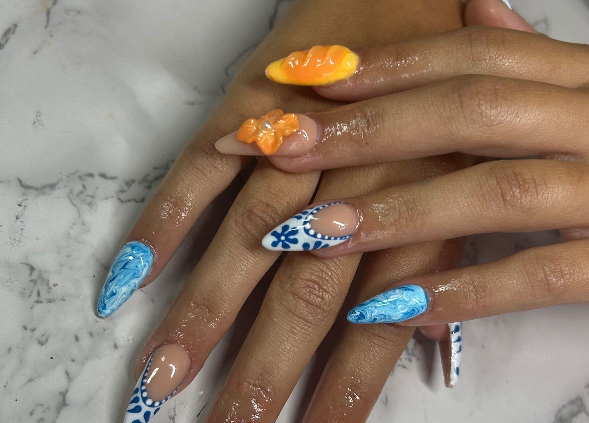 Unique nail art by Nails by Haylee in Virginia Beach, Virginia, featuring blue and orange designs.