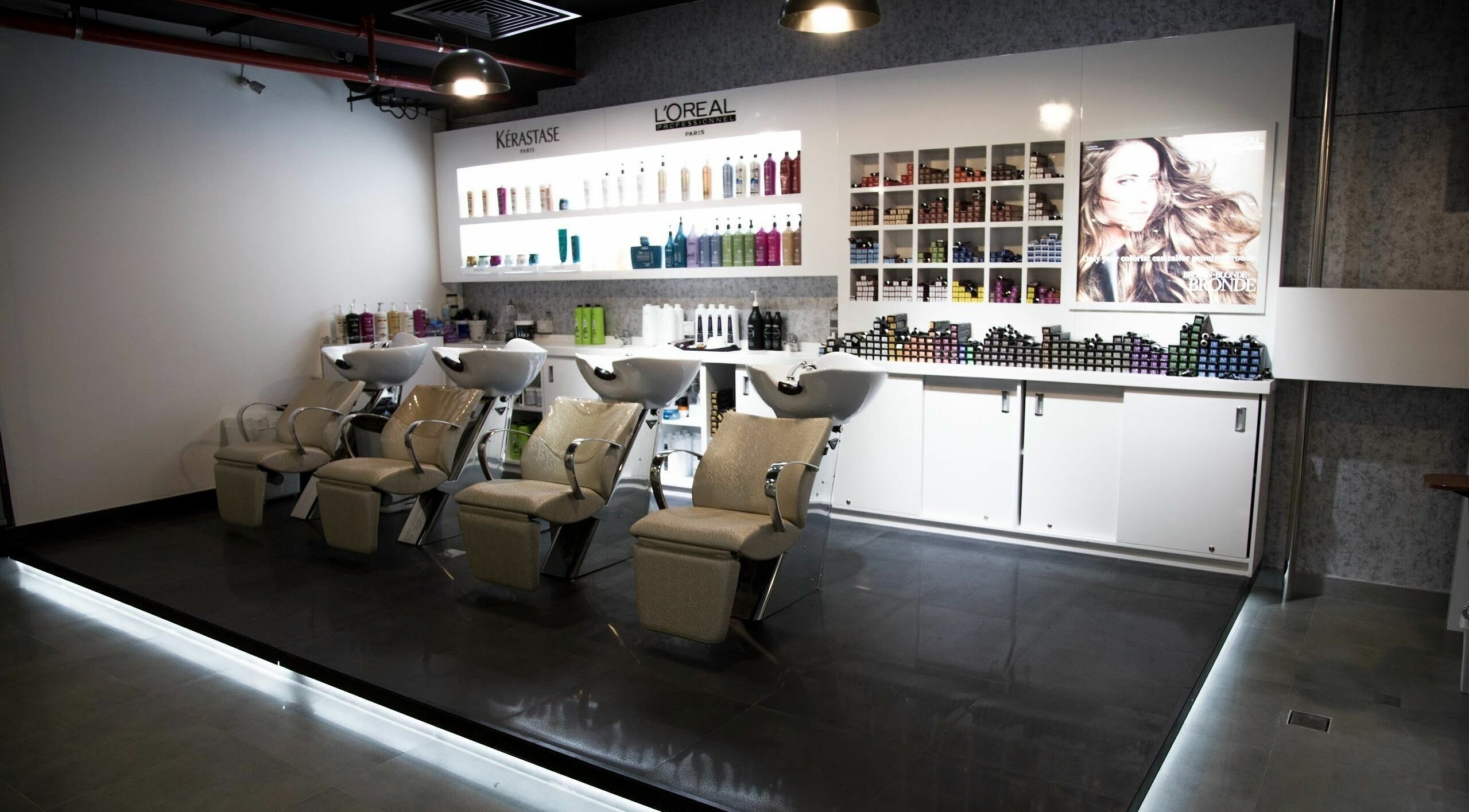 Interior of Roots Beauty Salon - Sunset Mall in Dubai, AE with modern washing stations and shelves full of products.