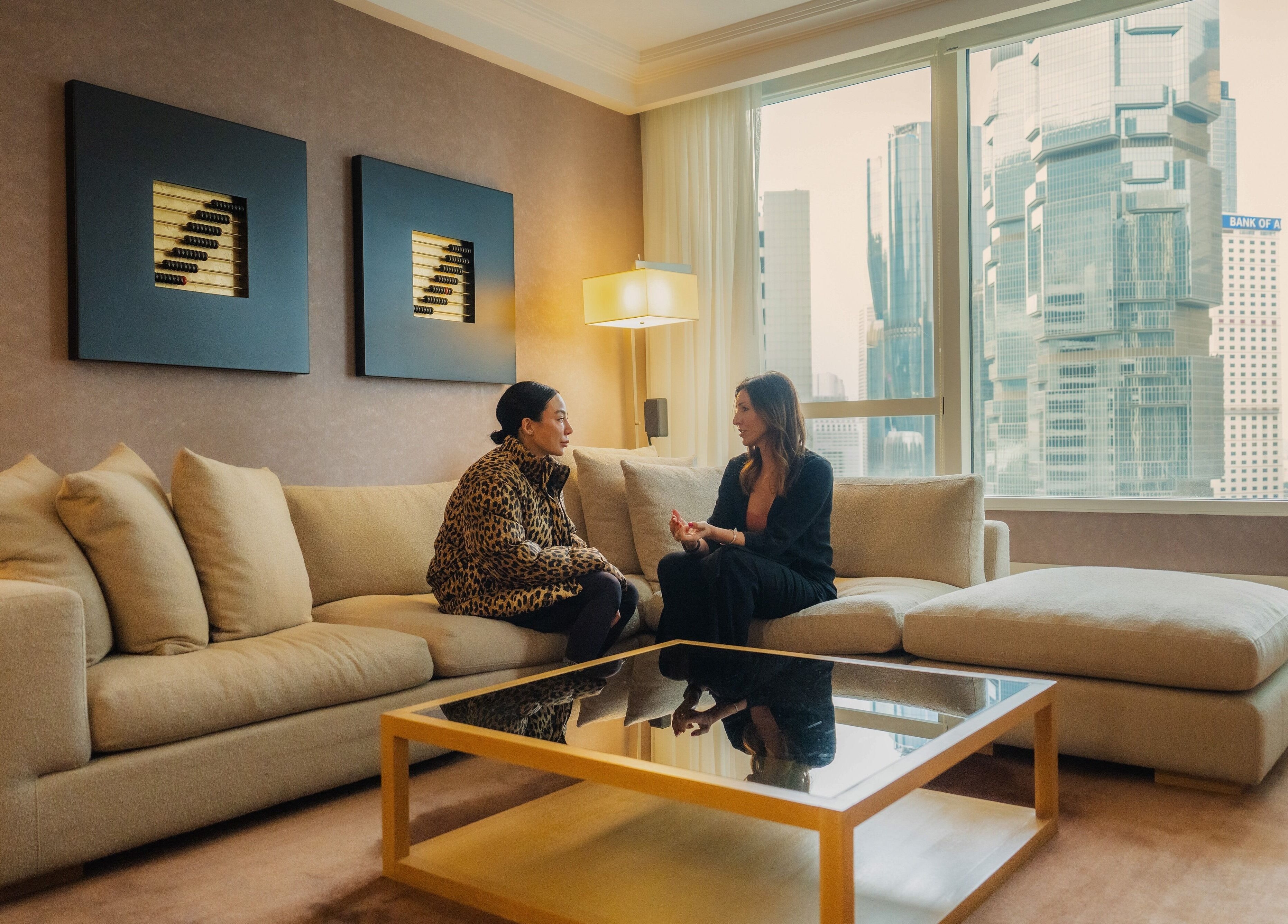 Two women chatting in a cozy living room at 10x Longevity, Hong Kong Island, Hong Kong Island, HK.