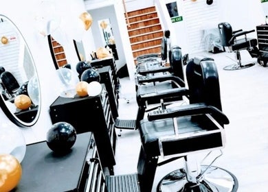 View of So Fresh Afro Barber in Bolton, England, GB showcasing sleek black chairs and festive balloons.