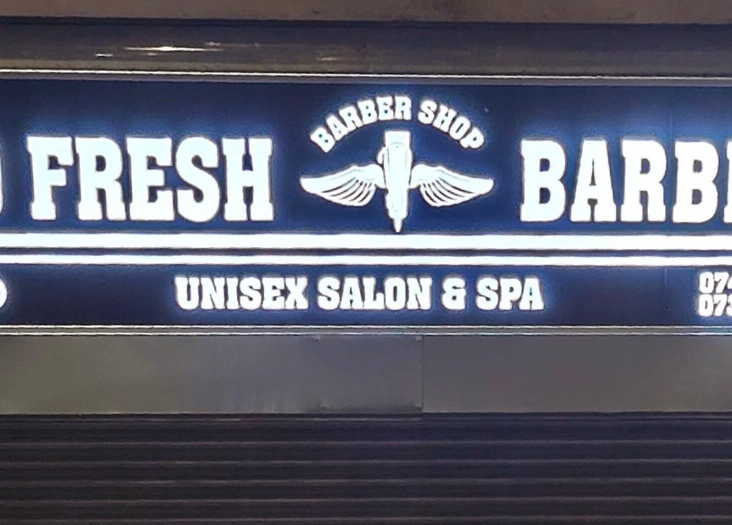Illuminated So Fresh Afro Barber sign in Bolton, England, GB, showcasing unisex salon and spa services.