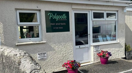 Exterior of Polgooth Village Salon in Polgooth, England, GB with a welcoming storefront and blooming flowers.