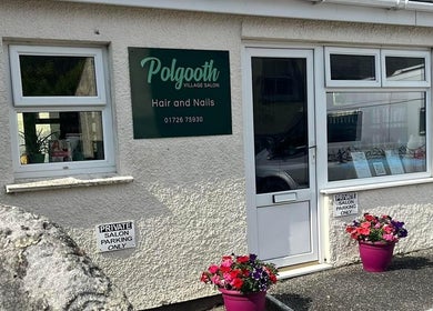 Entrance of Polgooth Village Salon in Polgooth, England, GB featuring vibrant flower pots.