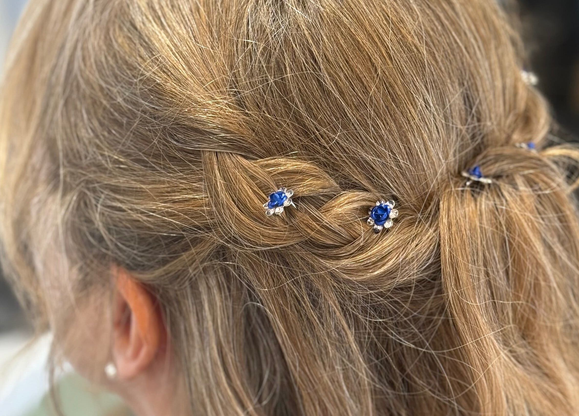 Close-up of a stylish braided hairstyle with blue gemstone pins at Polgooth Village Salon, Polgooth, England, GB.