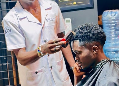 Expert hairstylist at Etunganun Grooming and Beauty Lounge, Kira Town, Central Region, UG, perfecting a haircut.