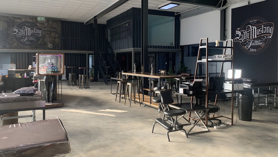 Spacious interior of Sally Mustang Tattoo Joburg in Johannesburg, Gauteng, ZA, with stylish seating and decor.