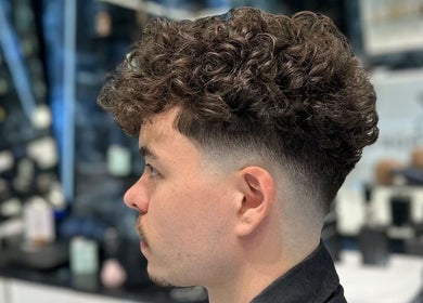Curly hairstyle with a fade at Fresh Fades Mens Barbershop, Dubai, Dubai, AE. Modern men’s grooming style.