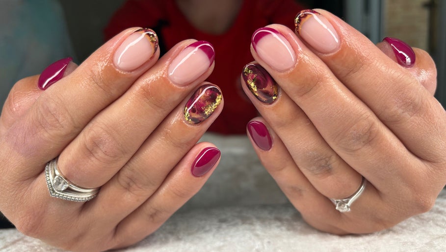 Stylish nail art at Jessica Bentley Beauty, Brough, England, GB. Red and gold designs on well-groomed hands.