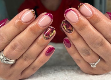Stylish nail art at Jessica Bentley Beauty, Brough, England, GB. Red and gold designs on well-groomed hands.