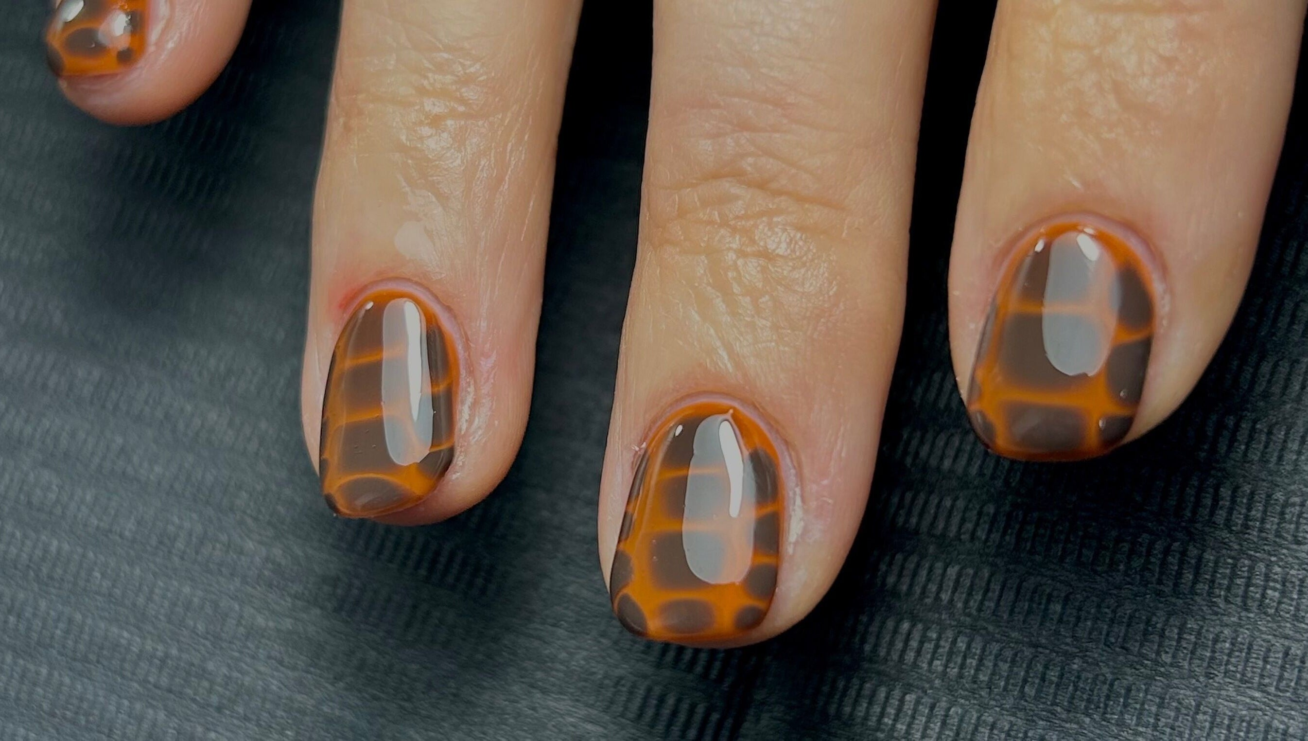 Stylish tortoiseshell nails by Nails by Jen in St Helens, England, GB on black background.