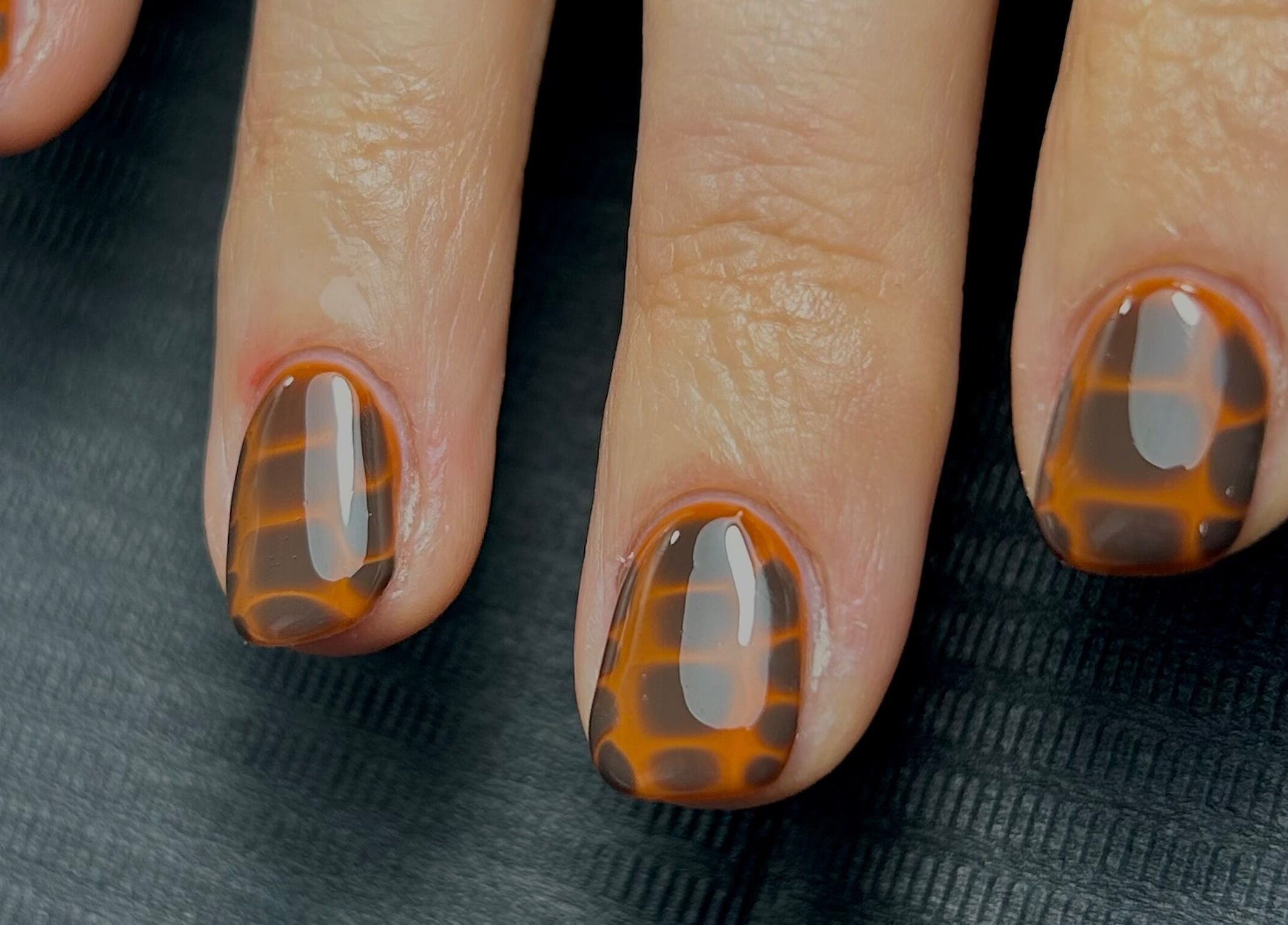 Stylish tortoiseshell nails by Nails by Jen in St Helens, England, GB on black background.