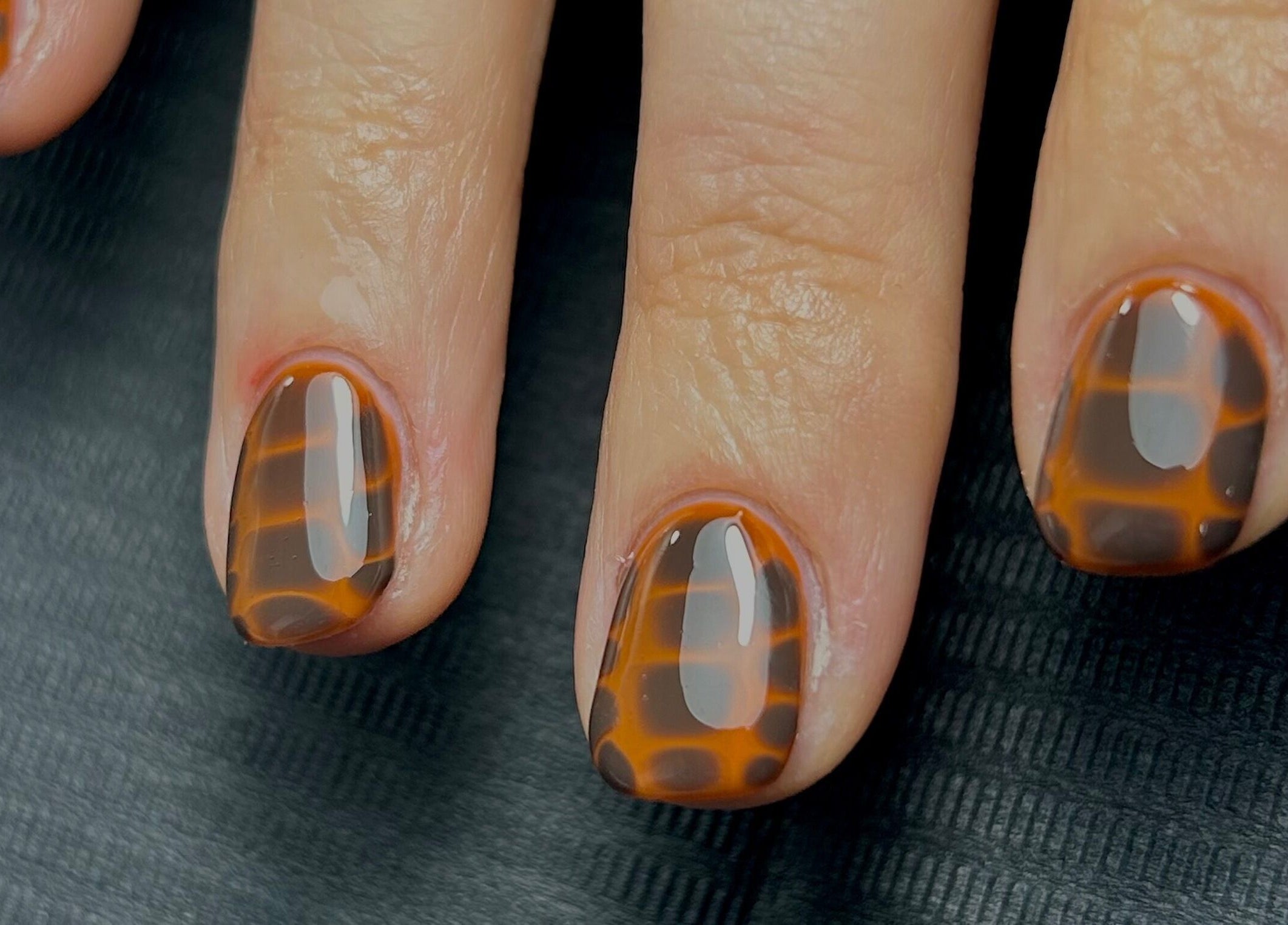 Stylish tortoiseshell nails by Nails by Jen in St Helens, England, GB on black background.