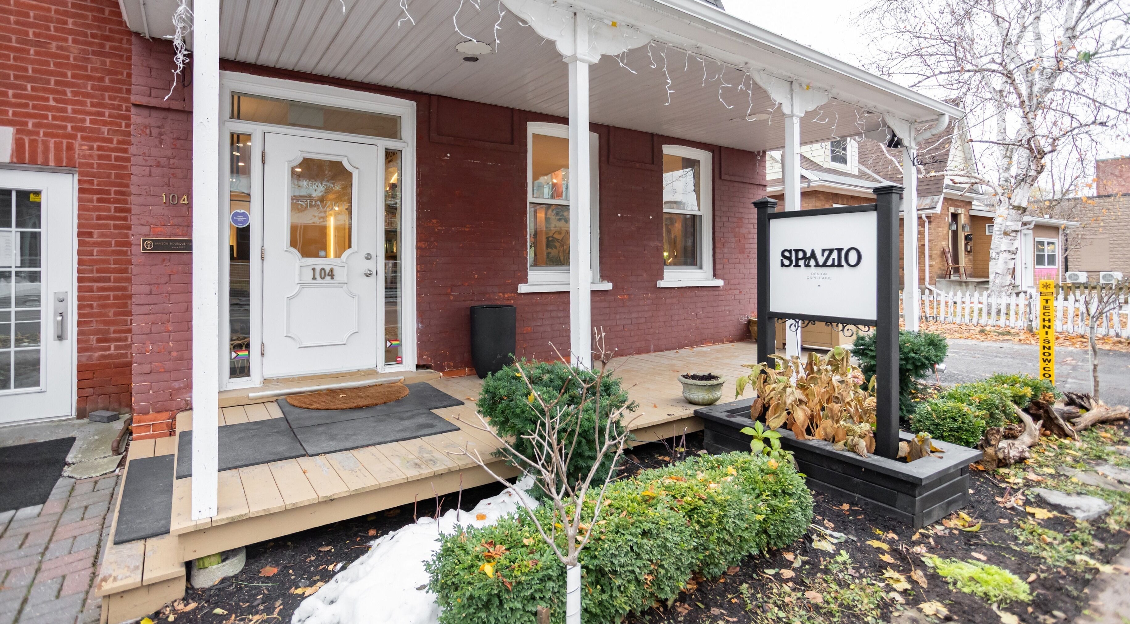 Entrée de Spazio Design Capillaire à Gatineau, Québec, CA, avec façade en briques et signalétique accueillante.
