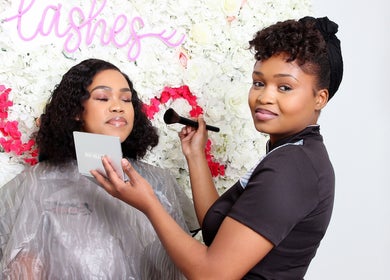 Makeup artist at Black Bird Beauty Spa in Roodepoort, Gauteng, ZA applying makeup with floral backdrop.