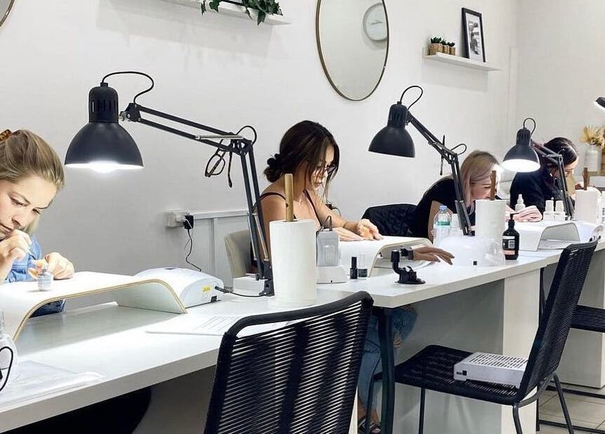 Customers receiving manicures at Nails by Belle in Budgewoi, NSW, AU. Bright, modern salon setting.