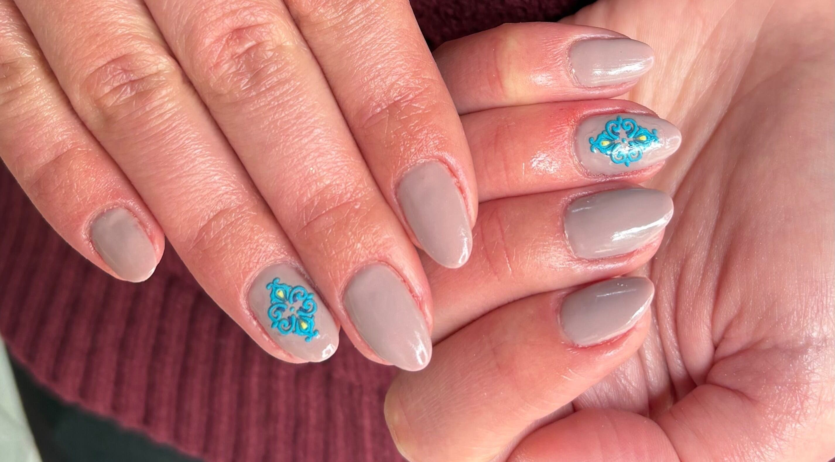 Elegant beige nails with blue floral art at Kim’s Beauty Center, Iż-żurrieq, MT.