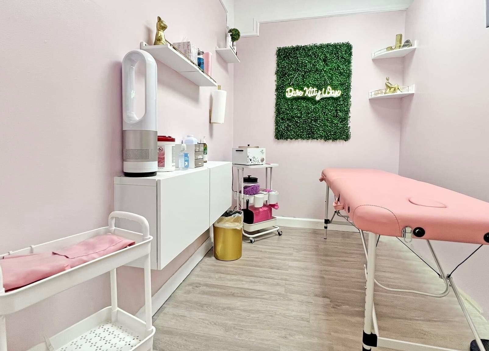 Tranquil spa room at Bare Kitty Wax in Inverness, Illinois, US, featuring a pink massage table and calming decor.