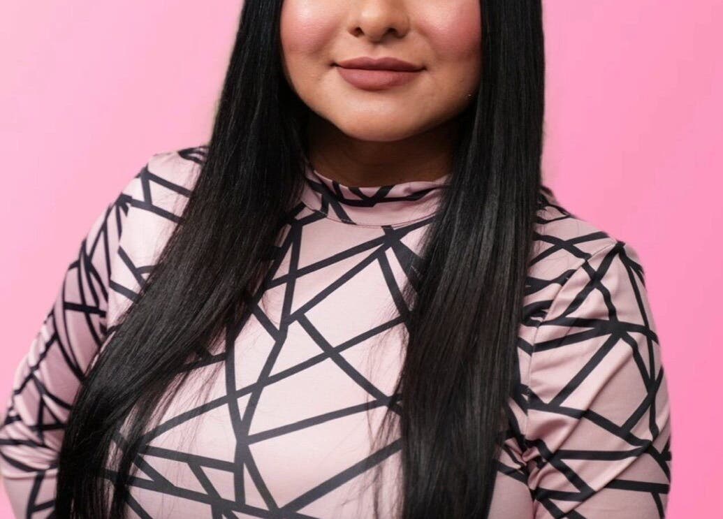 Close-up of a person with long hair and a geometric-patterned top at Bare Kitty Wax, Inverness, Illinois, US.