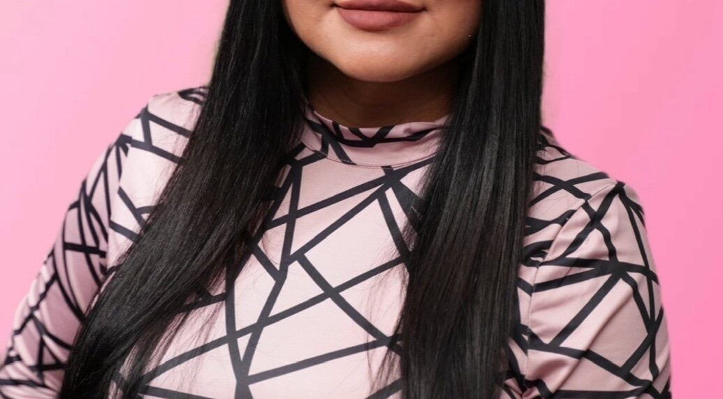 Close-up of a person with long hair and a geometric-patterned top at Bare Kitty Wax, Inverness, Illinois, US.