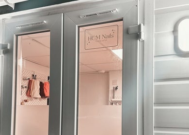Entrance of HCM Nails in Falmouth, England, GB, showcasing sleek door design and inviting interior.