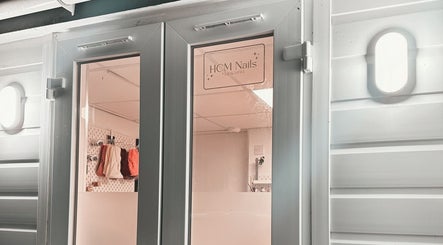 Entrance of HCM Nails in Falmouth, England, GB, showcasing sleek door design and inviting interior.