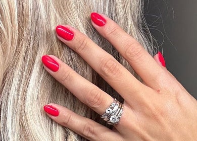 Close-up of a hand with vibrant red nails at HCM Nails, Falmouth, England, GB, showcasing elegant jewelry.