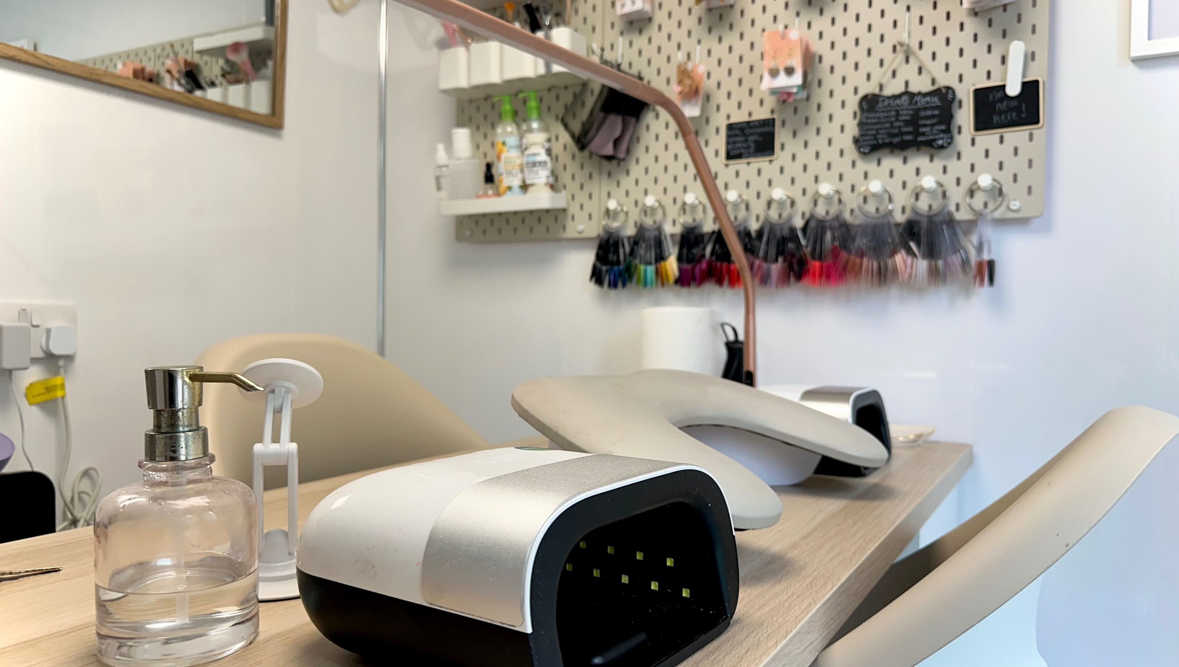 Modern nail salon setup at Nails by Hannah Morant, Falmouth, England, showcasing tools and color displays.
