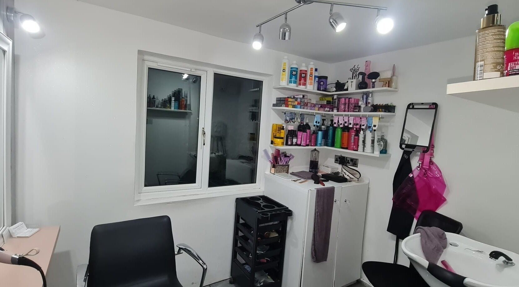 Cozy salon interior at Hairdressers Magic, Calne, England, GB showcasing sleek chairs and styling products.