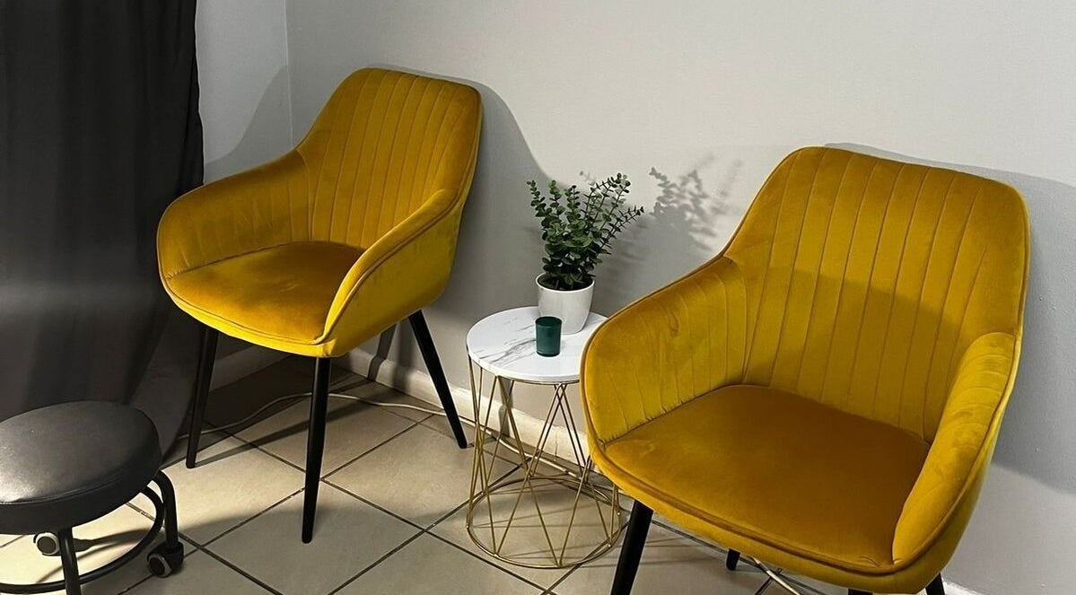 Cozy seating area in Honey Bliss Beauty, Cape Town, Western Cape, ZA with yellow chairs and a plant table.