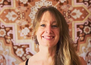 Joyful therapist at Lomi Massage Geelong, Newtown, Victoria, AU, with a calming tapestry backdrop.