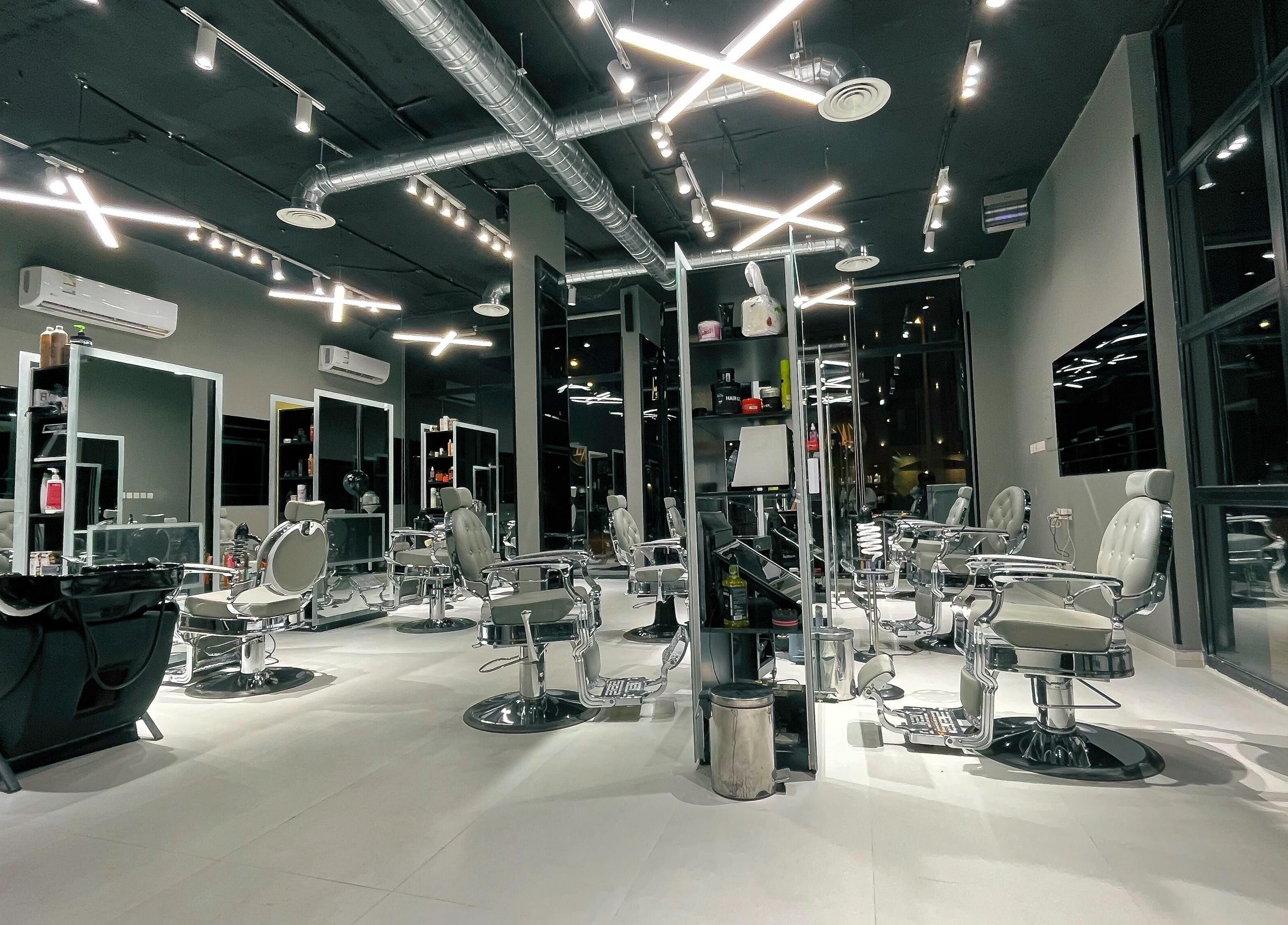 Interior of 1/2 Cuts Salon صالون هاف كت | Al Narjis in Riyadh, featuring sleek chairs and lighting.