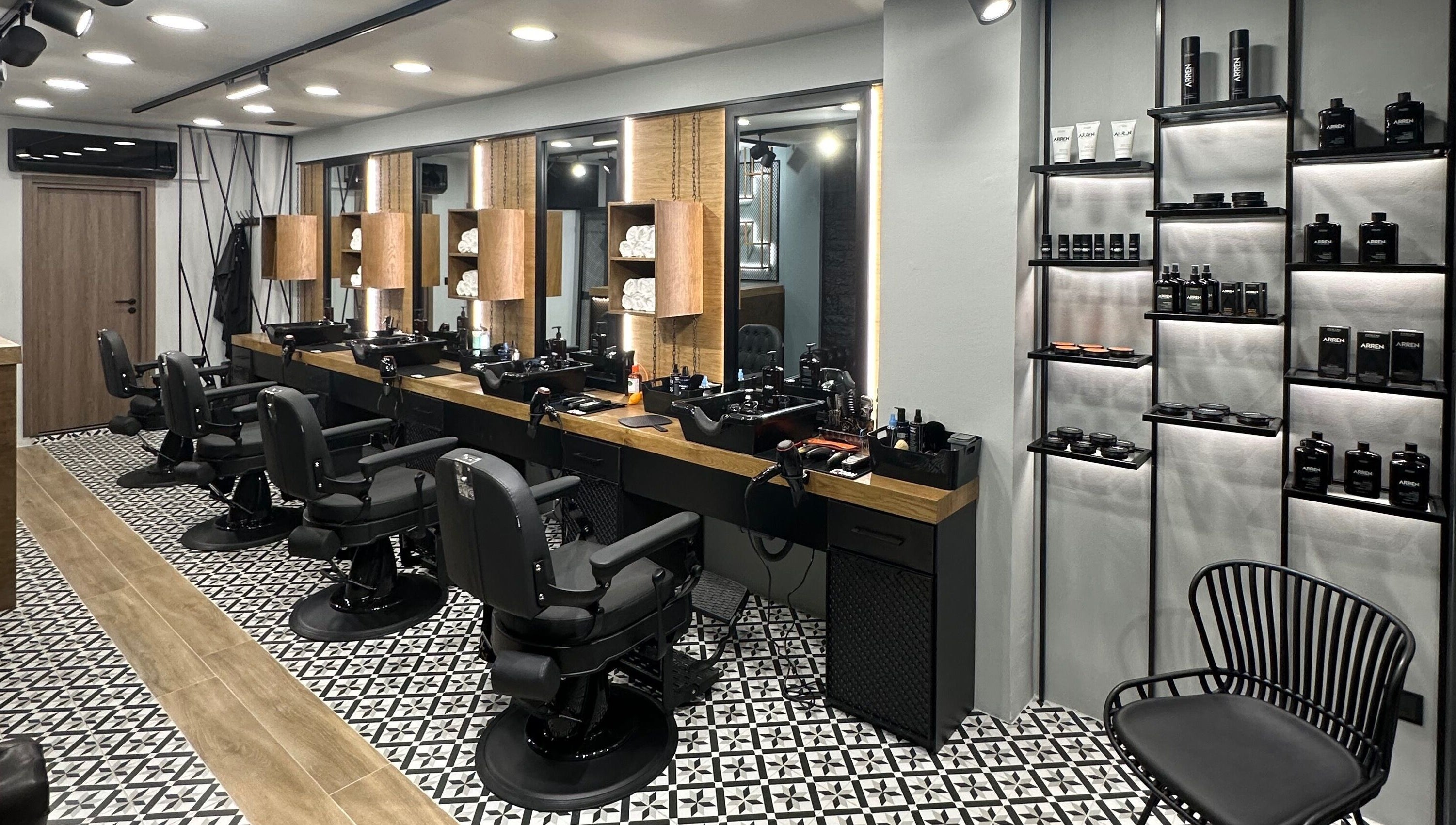 Κομψό εσωτερικό του King’s Barbershop Thermi στη Θέρμη, GR με όμορφες καρέκλες και προϊόντα περιποίησης.