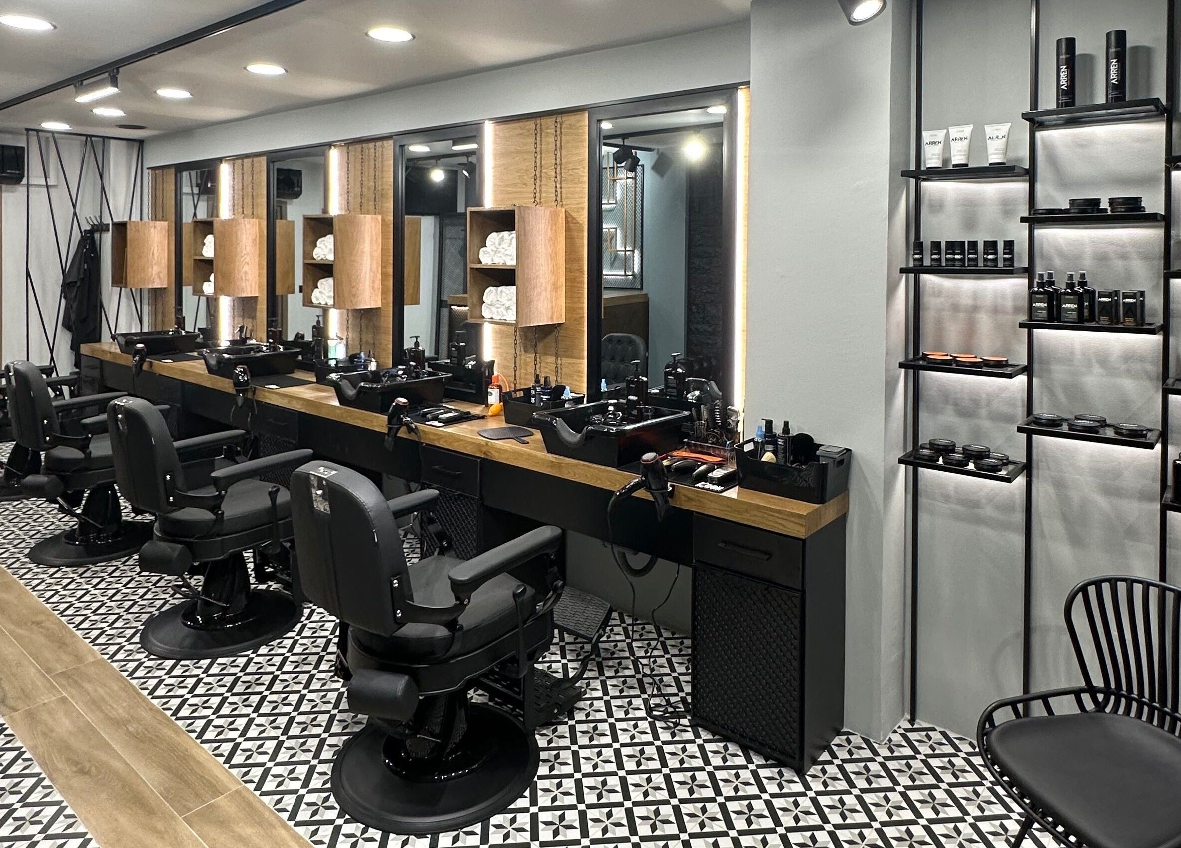 Κομψό εσωτερικό του King’s Barbershop Thermi στη Θέρμη, GR με όμορφες καρέκλες και προϊόντα περιποίησης.