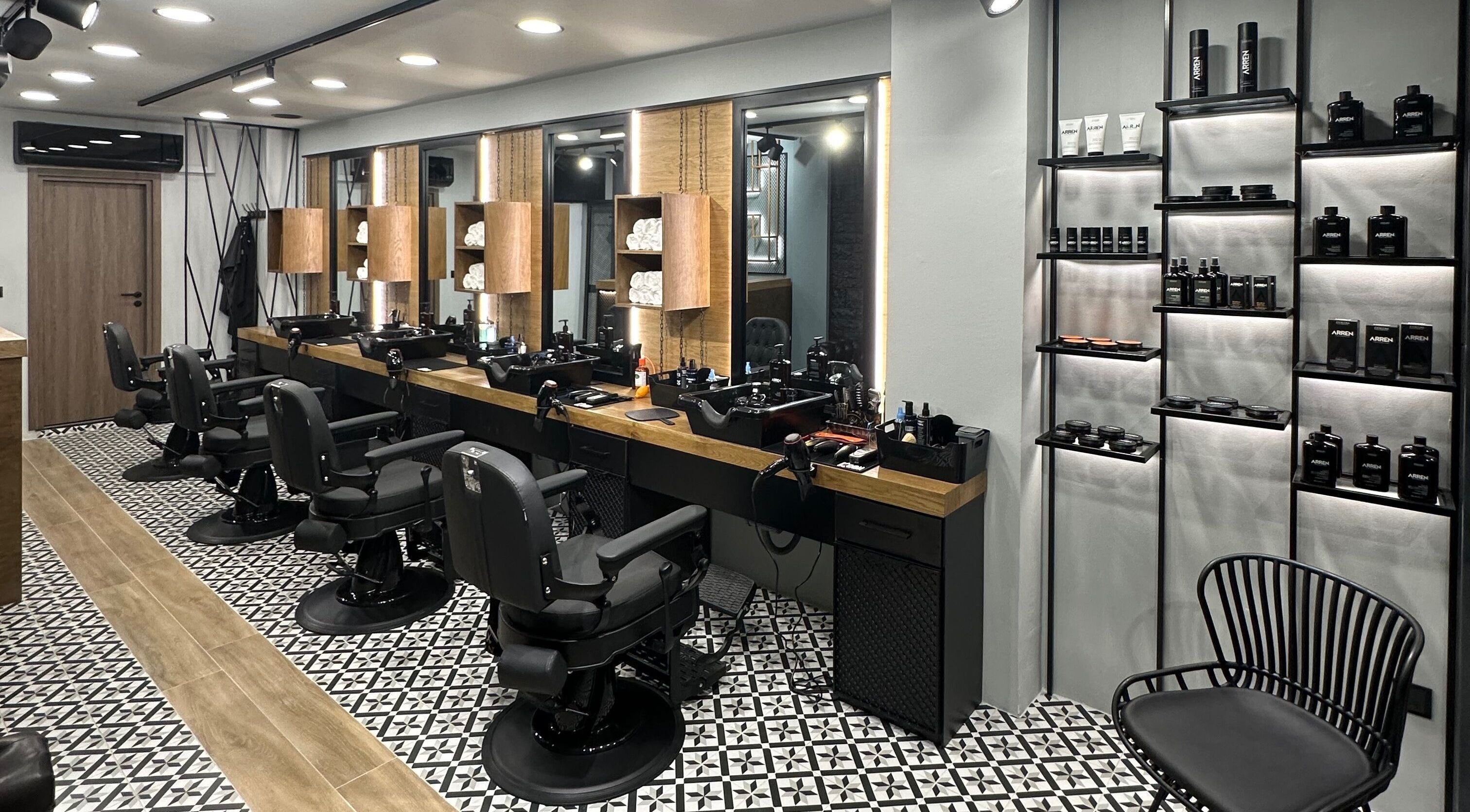 Κομψό εσωτερικό του King’s Barbershop Thermi στη Θέρμη, GR με όμορφες καρέκλες και προϊόντα περιποίησης.