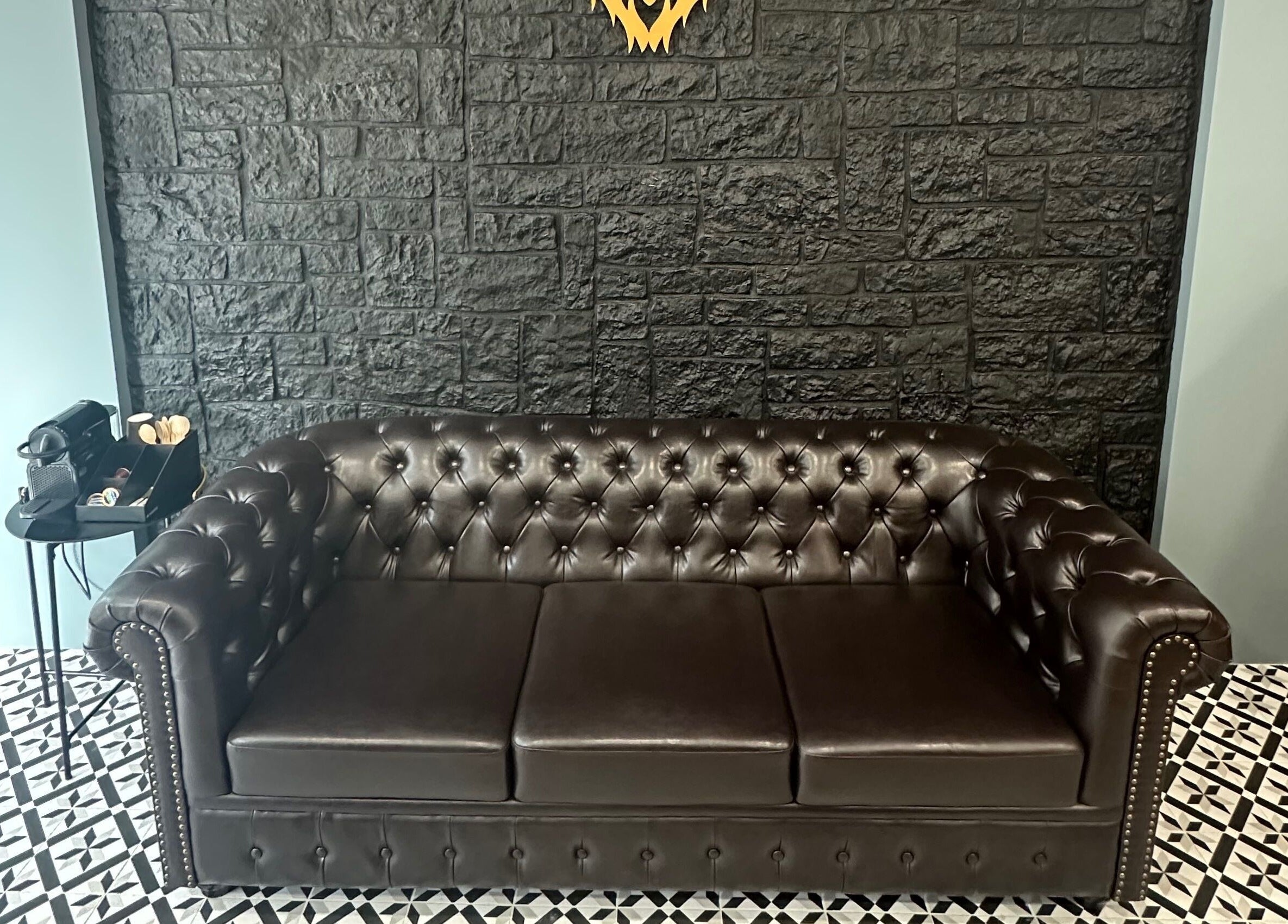 Βικτωριανικός καναπές στο King’s Barbershop Thermi, Θέρμη, GR. Μαύρος τοίχος και κομψό πλακάκι δαπέδου.