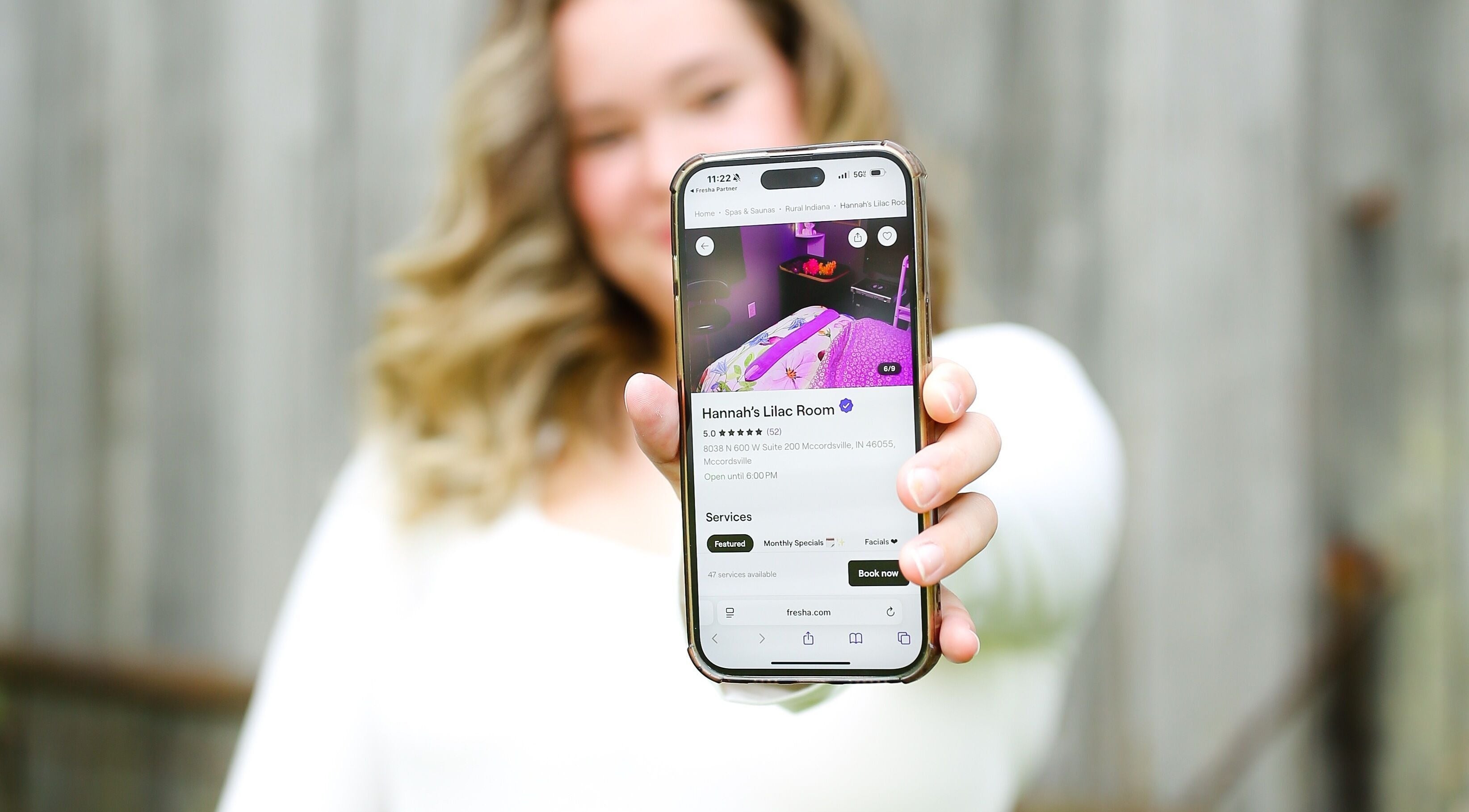 Person holds phone showing Hannah’s Lilac Room listing in Mccordsville, Indiana, US.