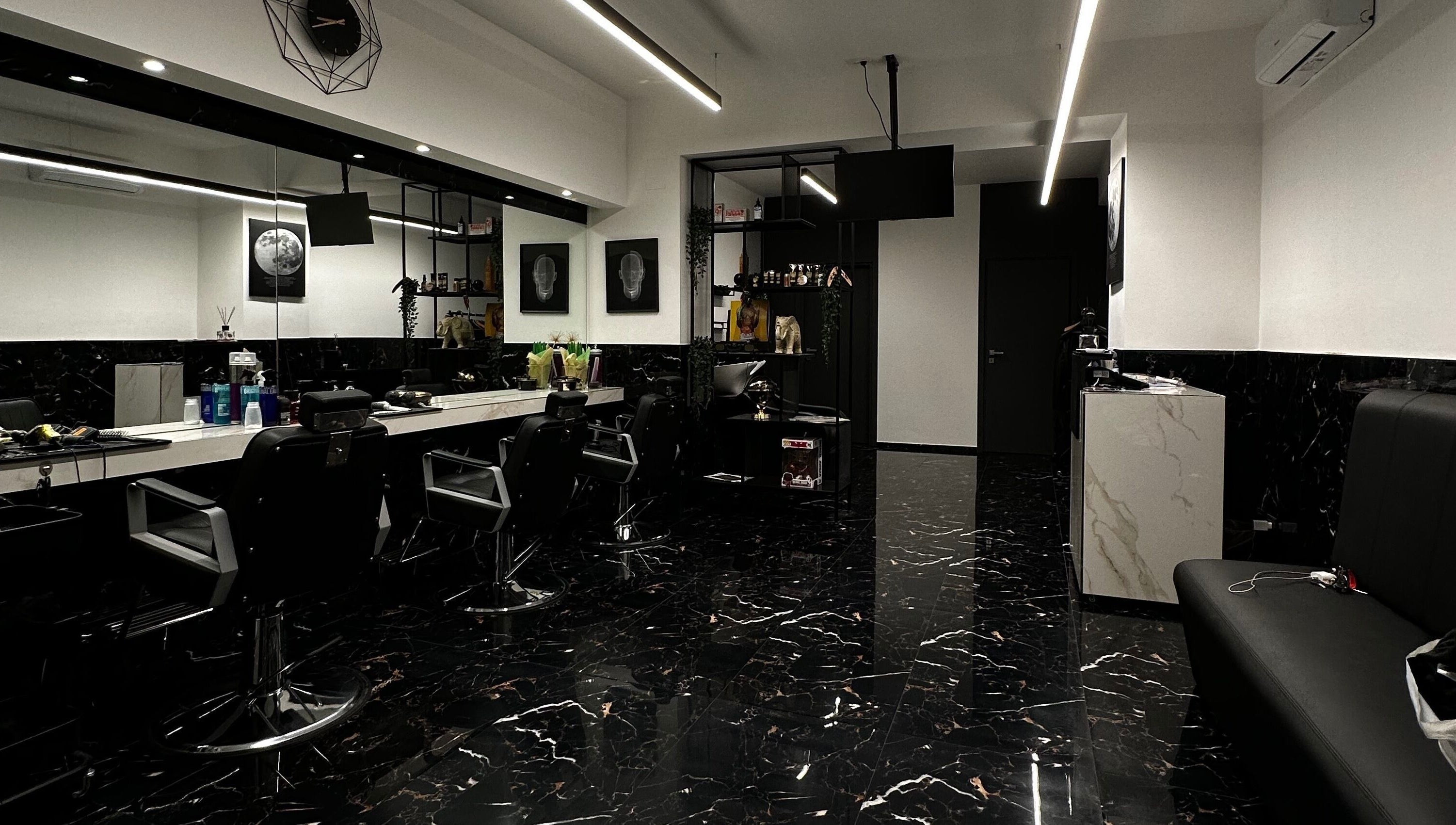Interno moderno del BELMORE HAIR STUDIO a Bari, Puglia, IT con sedie nere e pavimento in marmo lucido.