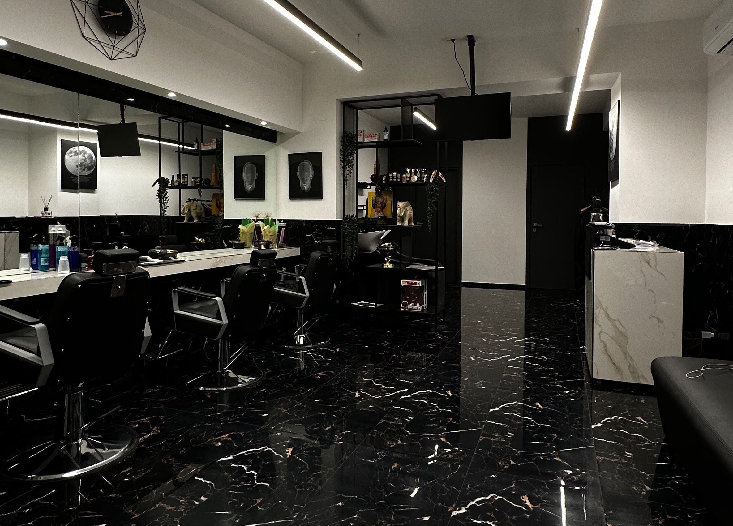 Interno moderno del BELMORE HAIR STUDIO a Bari, Puglia, IT con sedie nere e pavimento in marmo lucido.