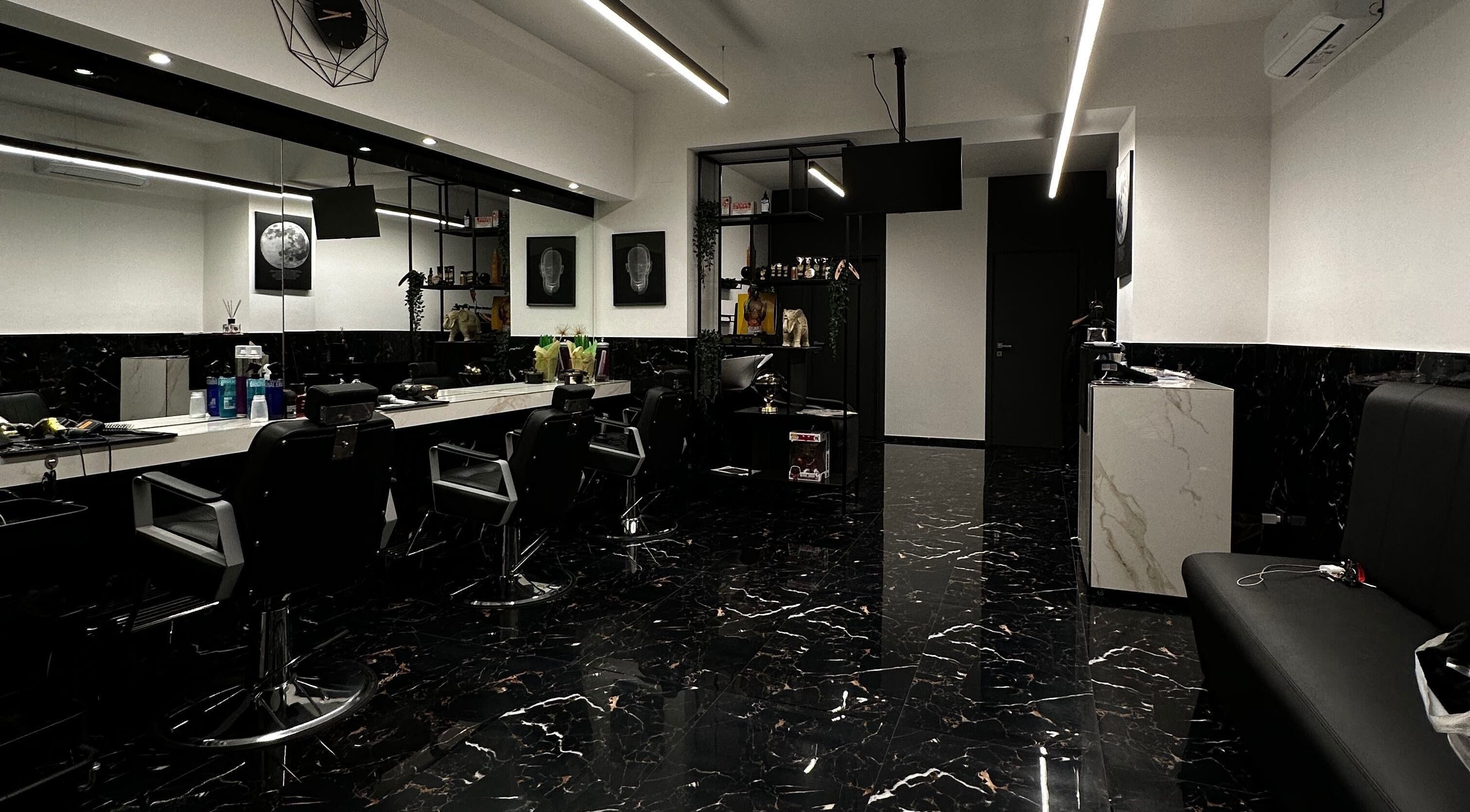 Interno moderno del BELMORE HAIR STUDIO a Bari, Puglia, IT con sedie nere e pavimento in marmo lucido.