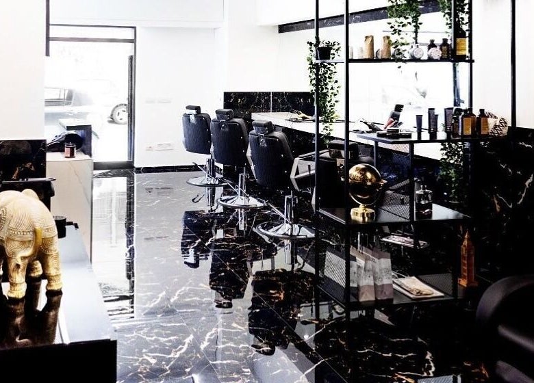 Interno sofisticato di BELMORE HAIR STUDIO a Bari, Puglia, con pavimenti in marmo e poltrone eleganti.