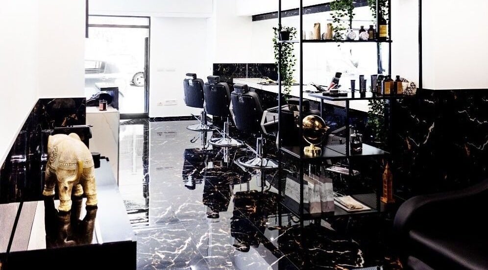 Interno sofisticato di BELMORE HAIR STUDIO a Bari, Puglia, con pavimenti in marmo e poltrone eleganti.