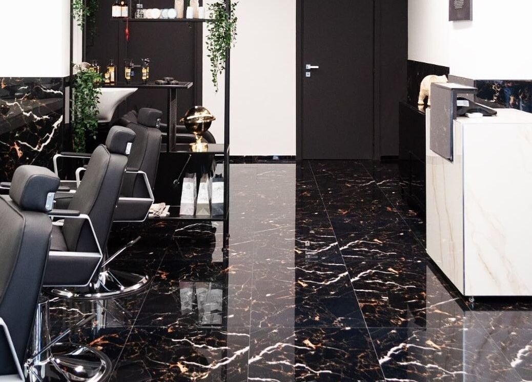 Interno elegante del BELMORE HAIR STUDIO, Bari, Puglia, IT, con sedie nere e dettagli di marmo.