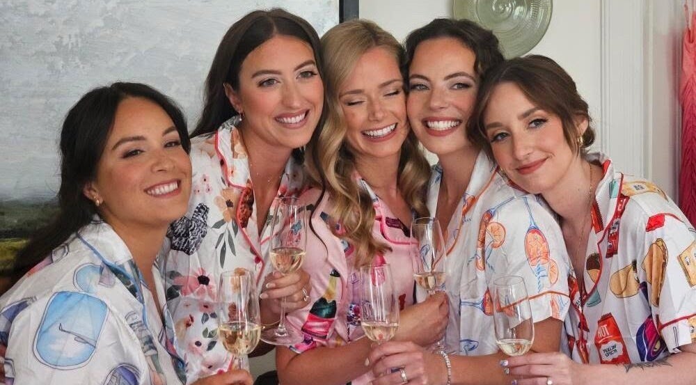 Group of smiling women in pajamas holding champagne at Glam By Shan in Newmarket, Ontario, CA.