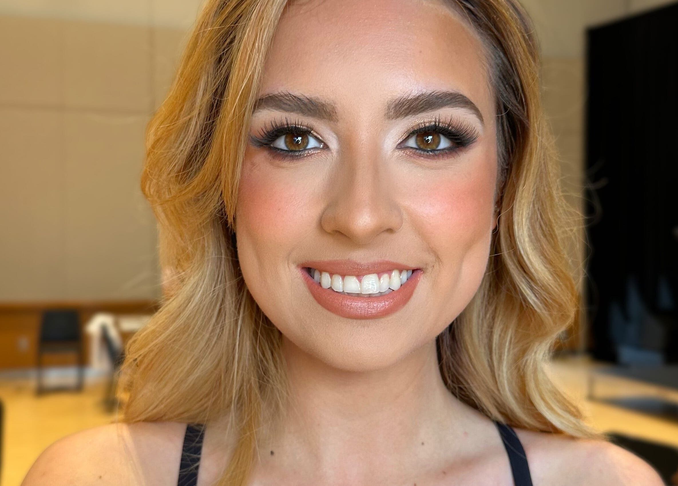 Smiling woman with makeup in Glam By Shan studio, Newmarket, Ontario, CA. Bright, professional setting.