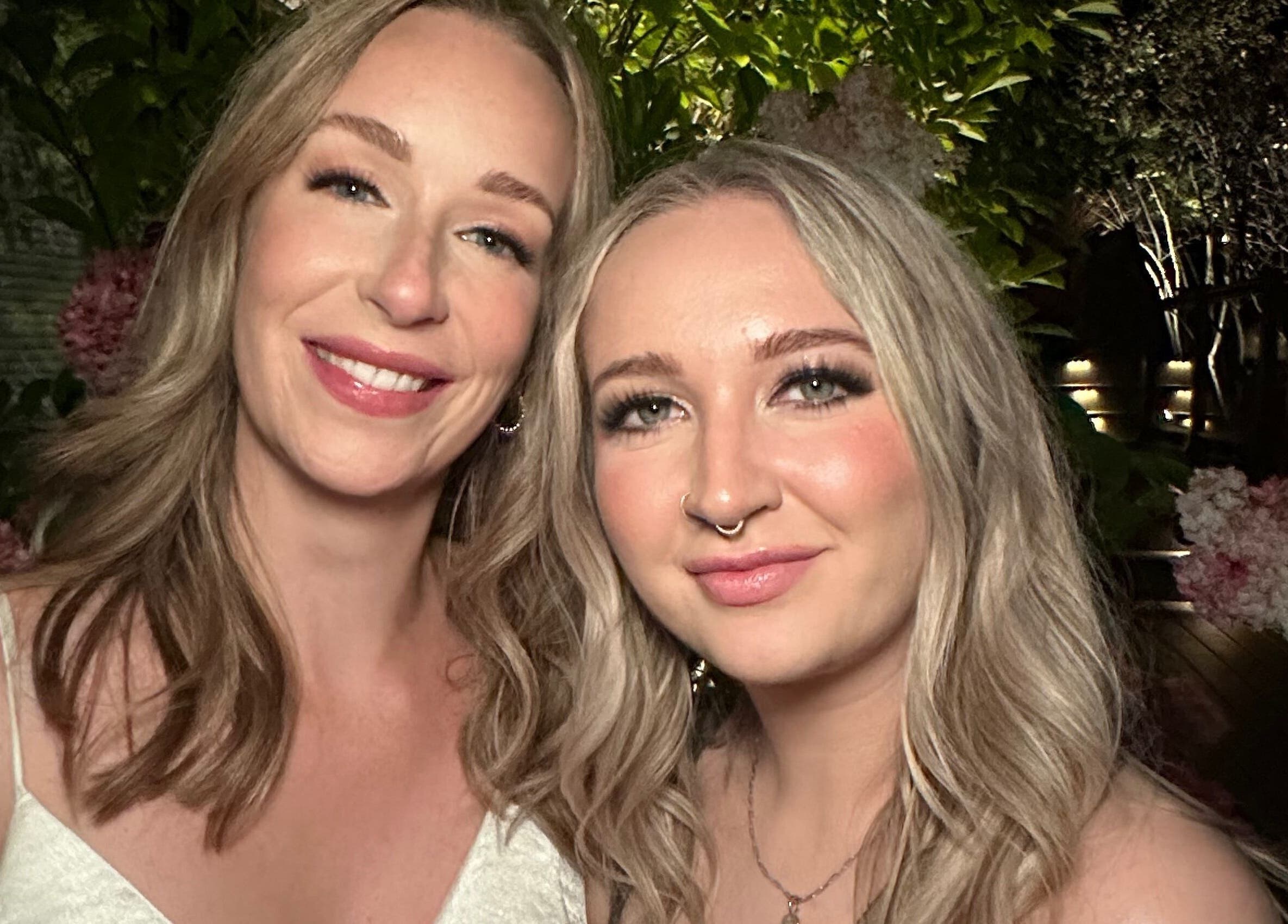 Two women smiling amid lush greenery at Glam By Shan, Newmarket, Ontario, CA.