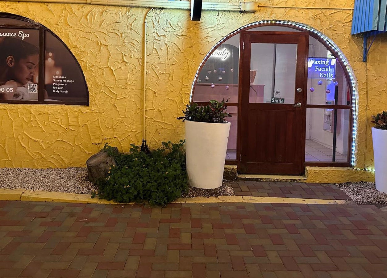 Front view of Pure Essence Spa, Kralendijk, Bonaire. Warm yellow facade with spa signage and decorative planters.