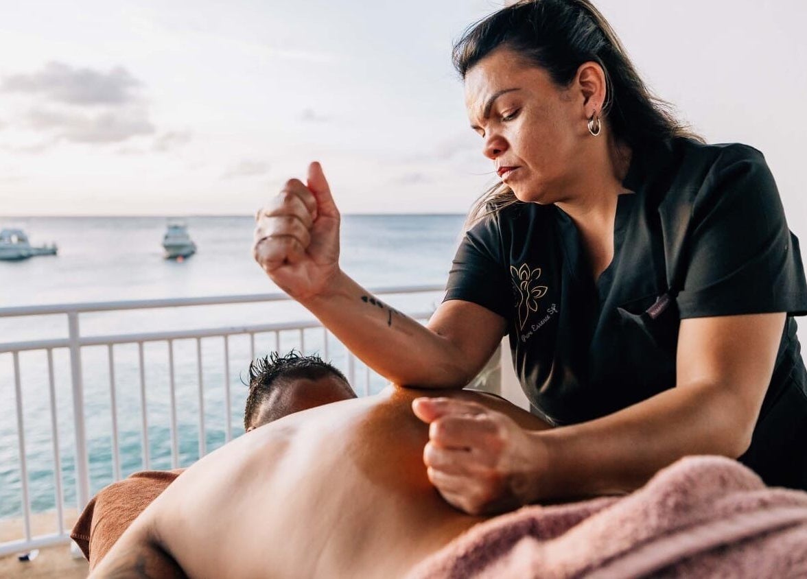 Therapist performing a massage at Pure Essence Spa, Kralendijk, Bonaire, overlooking the serene sea view.