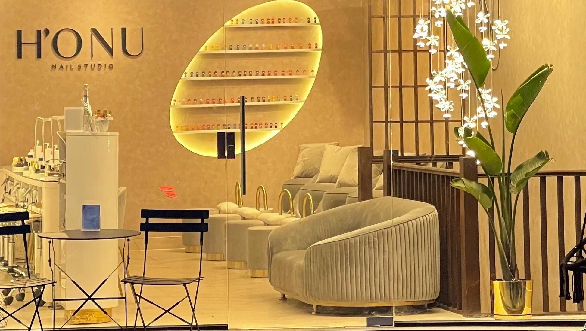 Interior of Honu Nail Studio - West Hampstead, London, England, GB. Cozy chairs, elegant decor, warm lighting.