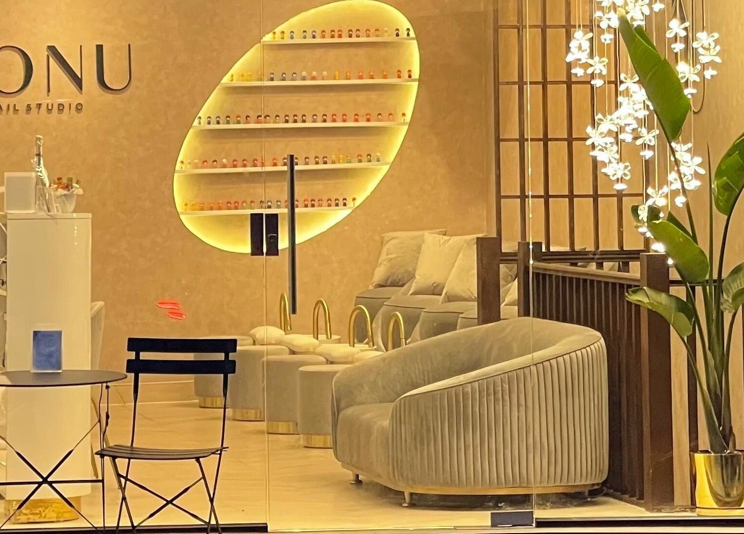 Interior of Honu Nail Studio - West Hampstead, London, England, GB. Cozy chairs, elegant decor, warm lighting.