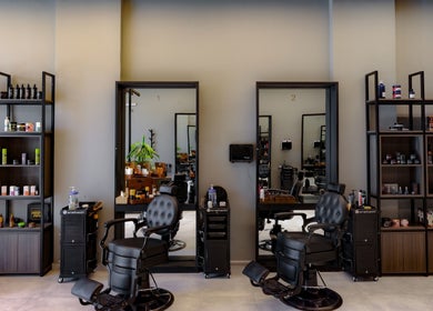 Elegant interior of The Address Barber | صالون العنوان قرطبة, Riyadh, SA with sleek chairs and shelves.